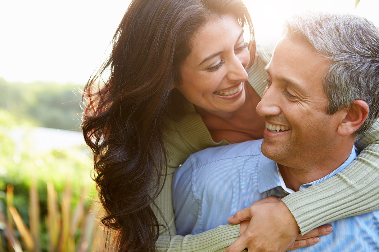 Middle aged man and woman smiling and hugging